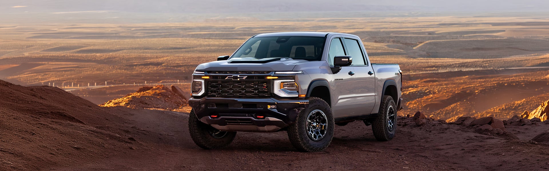 Chevy Silverado pickup truck on a rugged desert trail at sunset
